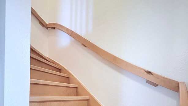 Una escalera de madera con barandilla que conduce a un piso superior.