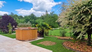 A hot tub in a landscaped garden with a paved patio. - Homerez - Villa in Ribérac (Ribérac)