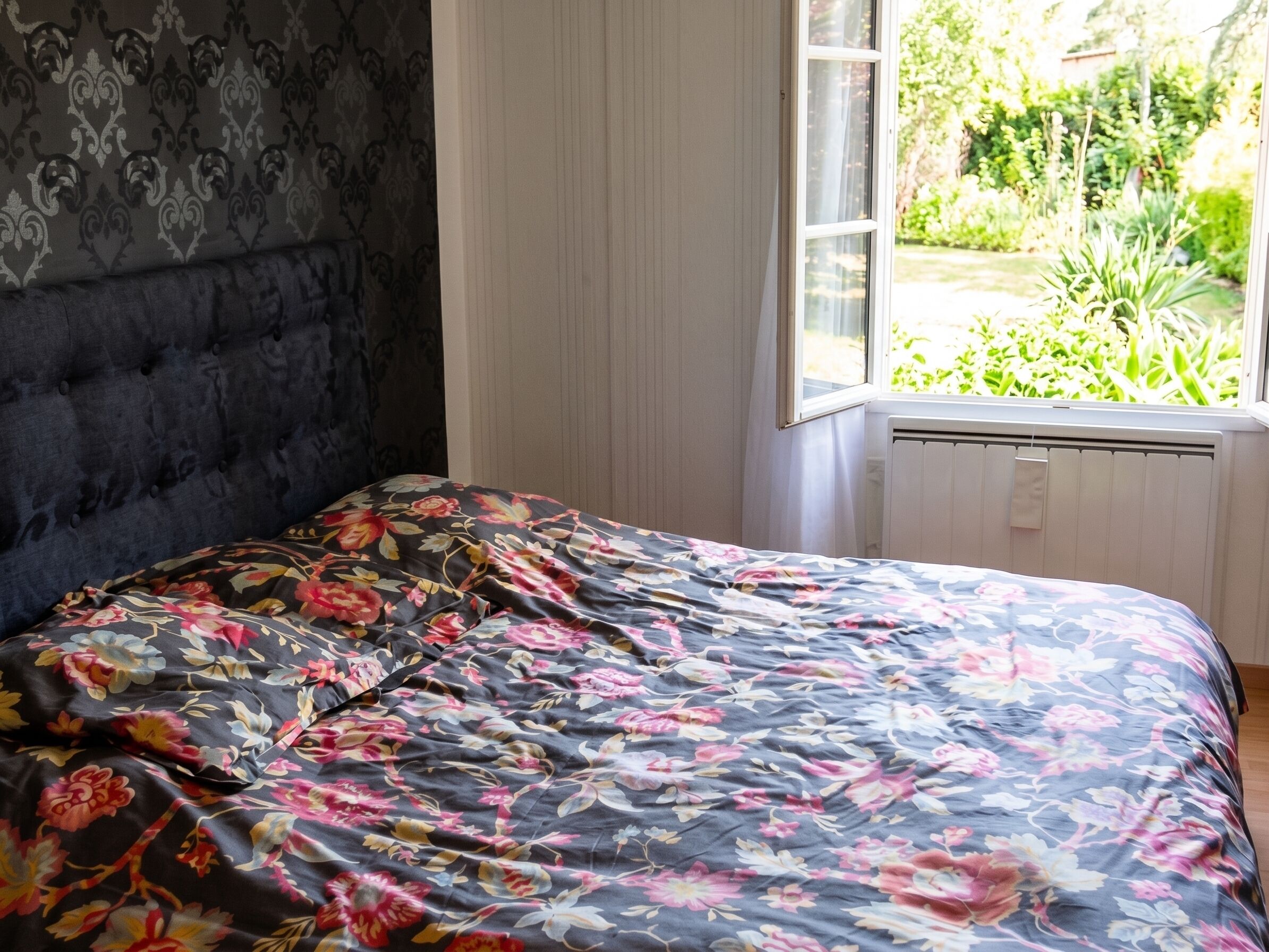 A bedroom with a bed, a window, and a radiator.