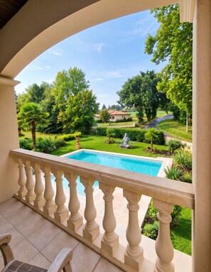 A pool with a view of a well-maintained garden and a distant house.