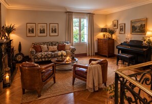 Un salon bien éclairé, avec un canapé, des fauteuils, une table basse, un piano et des tableaux encadrés accrochés au mur.