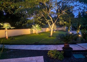 A well-maintained garden with a variety of trees, a neatly trimmed lawn, and a paved walkway.