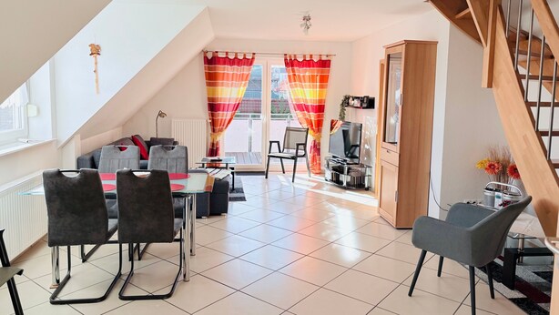 A modern living room with a dining area, a TV, and a staircase. - Achtern 8 - 70018, Germany (Wangerland)