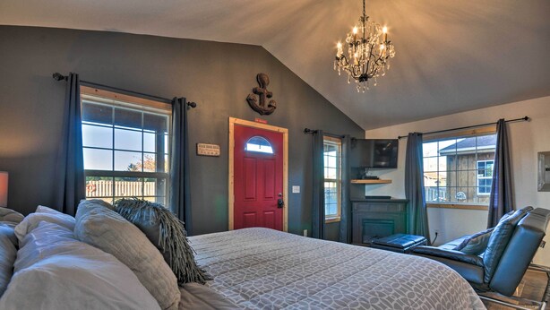 Ein Schlafzimmer mit einem großen Bett, einer roten Tür, einer Chandelüster und Blick ins Freie.