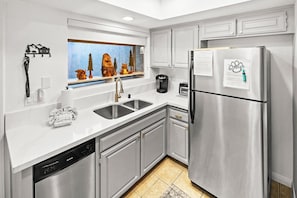 Une cuisine moderne dotée d’appareils électroménagers en acier inoxydable, d’une fenêtre offrant une vue sur les montagnes et d’un rebord de fenêtre décoratif.