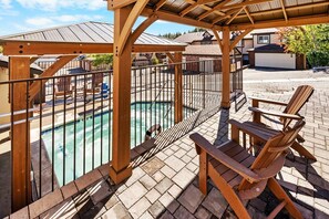 Ett trädäck med pool, en möblerad uteplats under tak och utsikt över ett bostadsområde.