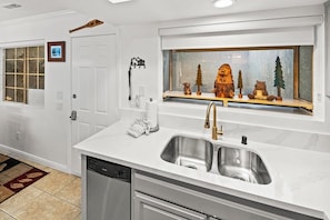A kitchen with a double sink, a dishwasher, and a window with decorative items. - Beautiful Townhouse! Walking Distance to Bear Mtn and Golf Course! Walk to Hiking! (Big Bear Lake)