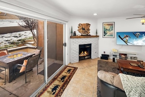 A living room with a fireplace, a TV, and a view of a snowy outdoor area.