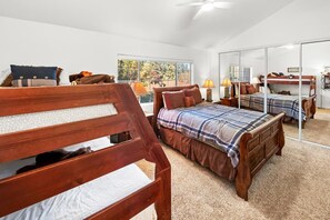 Ein Schlafzimmer mit einem großen Bett, einem Einzelbett und einem Etagenbett, alle mit Holzrahmen und vielen Kissen.