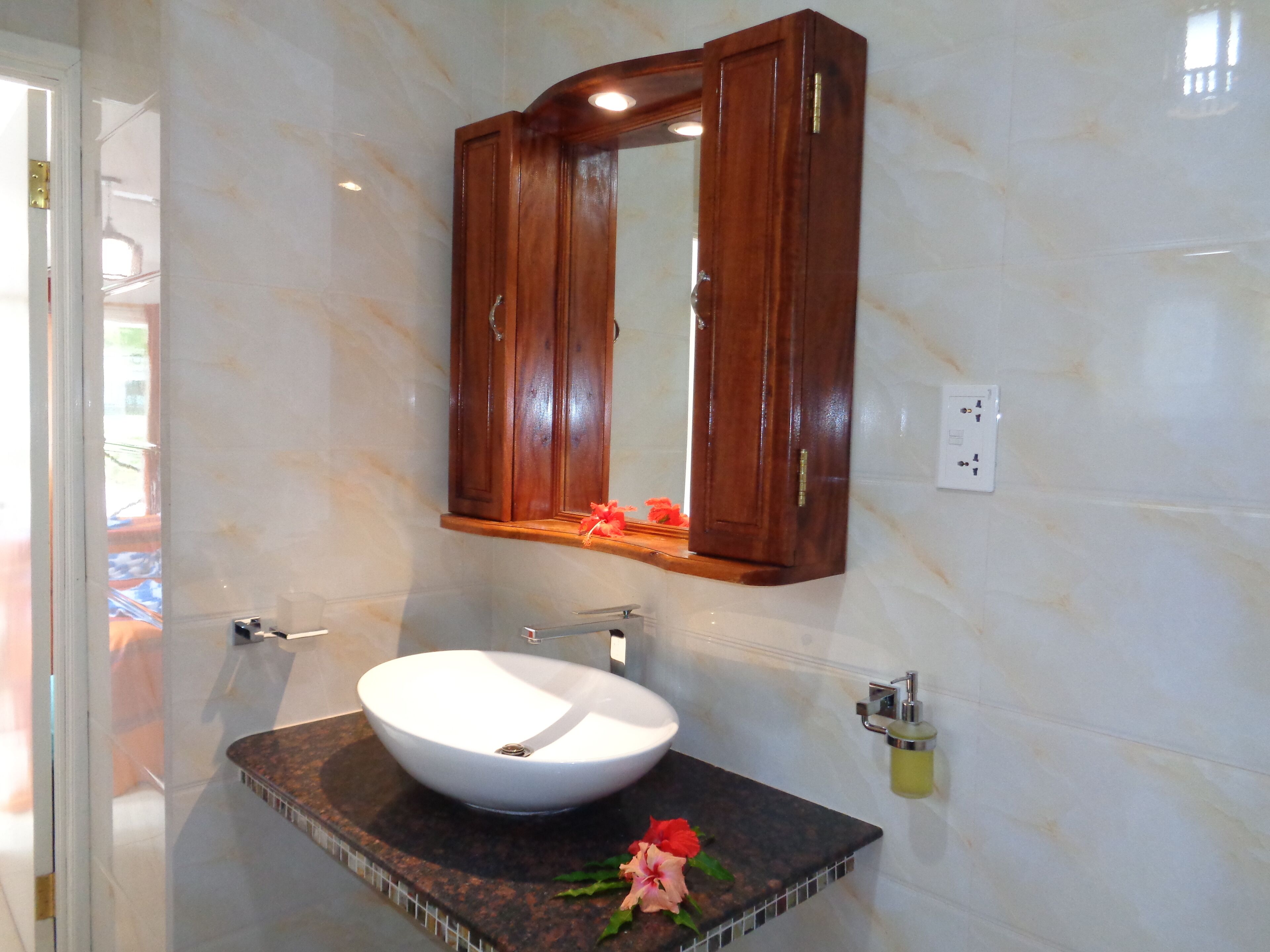 Un baño con un lavabo blanco, un armario de madera para medicinas y un espejo.