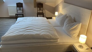 A neatly made bed with white linens in a room with a wooden headboard and two bedside lamps. - BürgerhausLöwen (Philippsburg)
