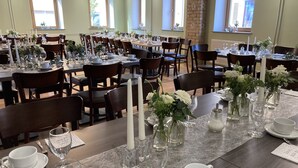 A dining area with multiple tables set for service, featuring white tablecloths, glassware, and floral centerpieces. - BürgerhausLöwen (Philippsburg)