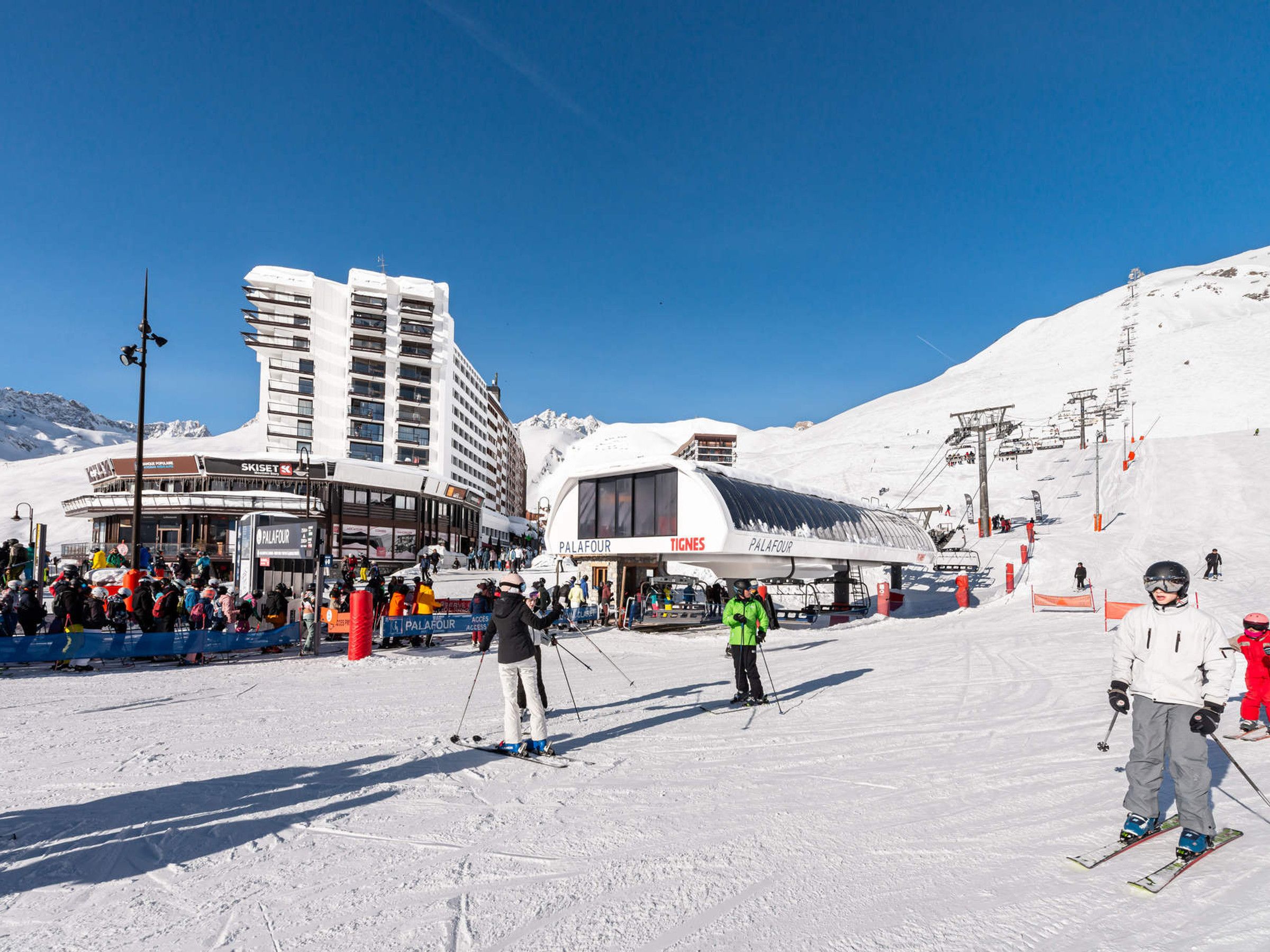 A ski resort with a large building labeled 'PalaFour' and a ski lift in operation.