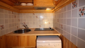 A compact kitchen with wooden cabinets, a sink, and a built-in dishwasher. - Classic studio for 2 in Tignes (Tignes)