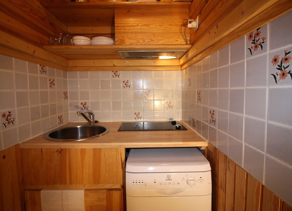 A compact kitchen with wooden cabinets, a sink, and a built-in dishwasher.