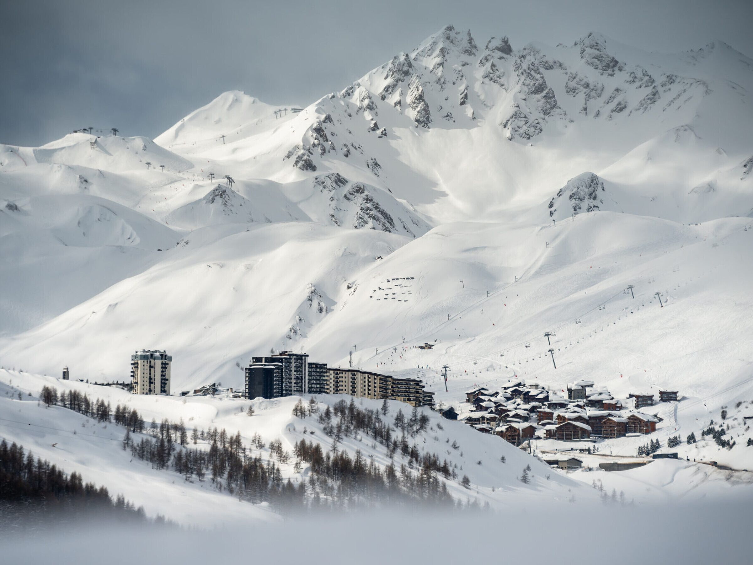 Eine verschneite Berglandschaft mit einem Skigebiet, einschließlich Gebäude und Skiliften.