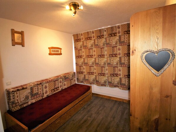 A small room with a wooden bench, a patterned curtain, a heart-shaped decoration on a door, and a wall-mounted light fixture. - Renovated studio 2 ppl – Tignes (Tignes)