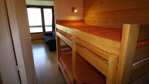 Une chambre avec un lit superposé, un plafond en bois et une fenêtre.