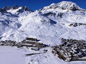 Eine verschneite Bergstadt mit einem großen Hotel und Skipisten.