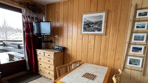 A wooden-paneled room with a wooden table and chairs, a television, a dresser, and a wall-mounted picture frame.