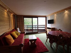 Quarto aconchegante com um sofá de madeira, uma mesa de jantar e uma grande janela com vista para um lago.