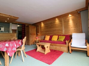 Um quarto acolhedor com um sofá de madeira, uma mesa de jantar com cadeiras e uma pequena mesa de madeira.
