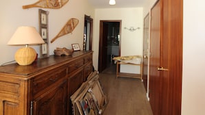 Un couloir avec une commode en bois, une lampe et des éléments de décoration murale.