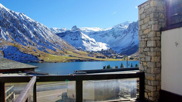 Un balcon avec vue sur un lac, des montagnes et une ville en arrière-plan.