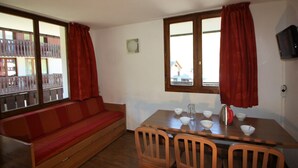 A room with a wooden sofa, a dining table with chairs, and a window with curtains. - Near slopes, 2 rooms for 6 people in Tignes (Tignes-Val Claret)