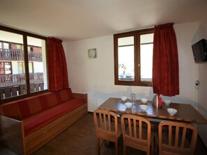 A room with a wooden sofa, a dining table with chairs, and a window with curtains. - Near slopes, 2 rooms for 6 people in Tignes (Tignes-Val Claret)