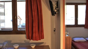 A room with a wooden table, a bed with red bedding, and a window with curtains. - Near slopes, 2 rooms for 6 people in Tignes (Tignes-Val Claret)