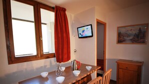 A dining area with a wooden table, four chairs, a television mounted on the wall, and a painting on the wall. - Near slopes, 2 rooms for 6 people in Tignes (Tignes-Val Claret)