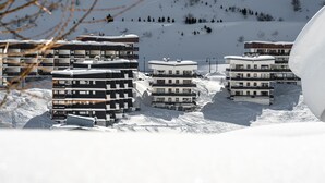 Area montuosa innevata con moderni edifici a più piani, probabilmente una stazione sciistica.