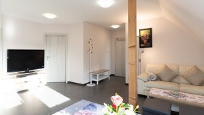 A living room with a flat-screen TV, a sofa, a coffee table, and a painting on the wall. - Vacation apartment Havana - Holiday apartments former health department (Ueckermünde)