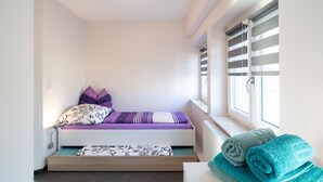 A small, modern bedroom with a bed, pillows, a window with blinds, and a radiator. - Vacation apartment Havana - Holiday apartments former health department (Ueckermünde)