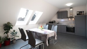 A modern kitchen with grey cabinets, a microwave, and a dining area with a table and chairs. - Vacation apartment Havana - Holiday apartments former health department (Ueckermünde)