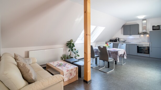 A modern loft apartment with a dining area, kitchenette, and a large window. - Vacation apartment Havana - Holiday apartments former health department (Ueckermünde)