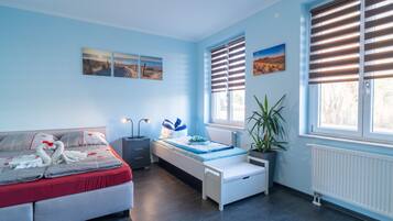 Ein Zimmer mit Bett, Nachttisch, Lampe, Topfpflanze und Bildern an den Wänden.