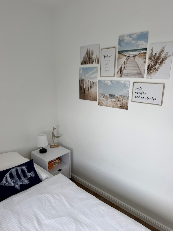A bedroom with a bed, a nightstand with a lamp, and wall art.