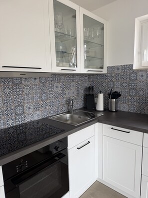 Een moderne keuken met witte kasten, een zwart aanrecht en een backsplash met patroon.
