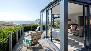 A modern house with a glass-enclosed balcony overlooking a coastal view.