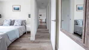 A bedroom with a bed, bedside table, and a large mirror.