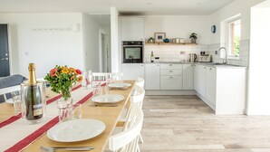 A modern kitchen with white cabinets, a built-in oven, and a countertop with a toaster and kettle.