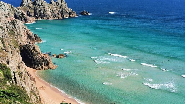A coastal landscape with rocky cliffs and a clear turquoise sea.