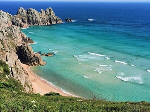 A coastal landscape with rocky cliffs and a clear turquoise sea. - Blue Sky: gorgeous home with stunning sea views: walk to beach, shops, cafe, pub (Penzance)