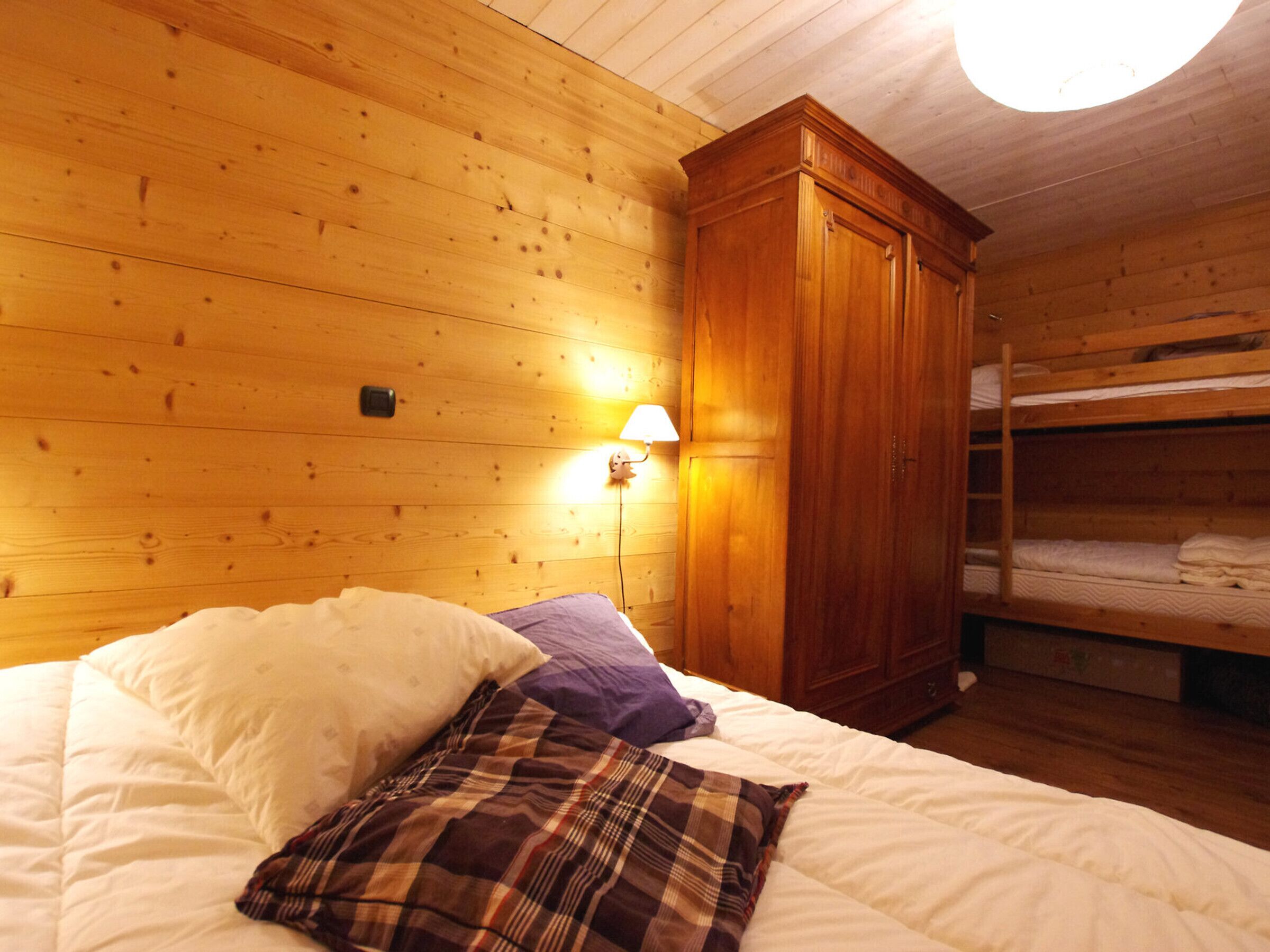 Een houten kamer met een stapelbed, een kledingkast en een bedlampje.
