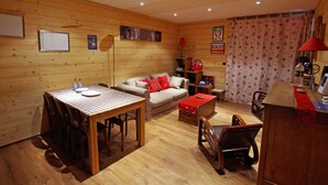 L’intérieur d’un chalet chaleureux, avec une table à manger en bois, un canapé et un fauteuil rouge.