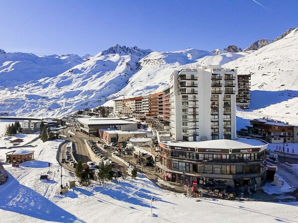 A snow-covered mountain town with a prominent hotel featuring a ski lift and a view of the surrounding snowy landscape.