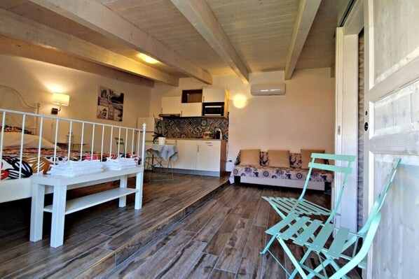 A cozy room with a bed, a bench, a sofa, and a dining area with a table and chairs.
