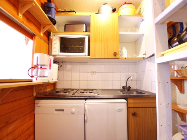 A compact kitchen with wooden cabinets, a microwave, a dishwasher, and a sink.